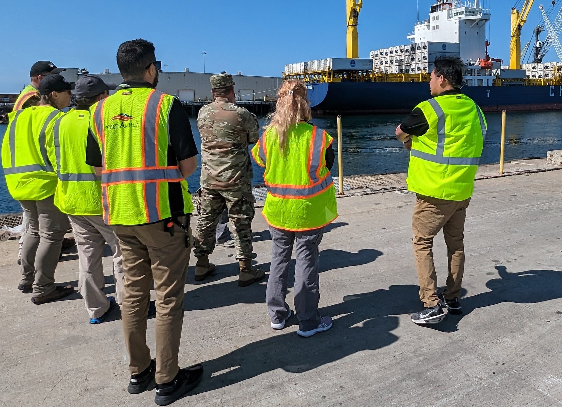 People surveying a port with a cargo ship.