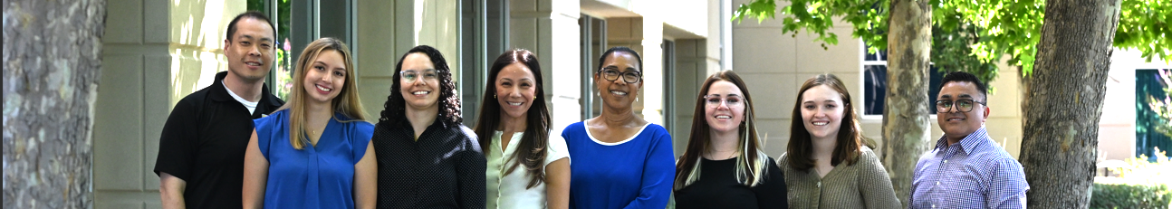 A diverse group of ODEI and Listos California team members stand side by side outdoors on the Cal OES campus, smiling and facing the camera. The people are dressed in professional attire, with trees and a building visible in the background, reflecting teamwork, collaboration, and inclusive leadership.