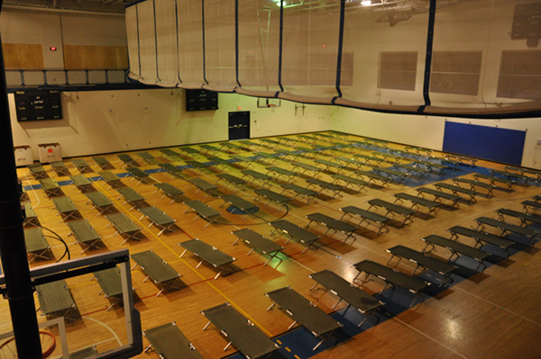 A gymnasium filled with many cots.