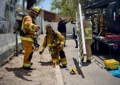 Firefighters working and carrying a ladder.