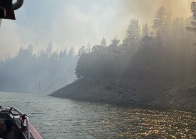 Smoke-filled sky from the view of a fire boat on a lake.
